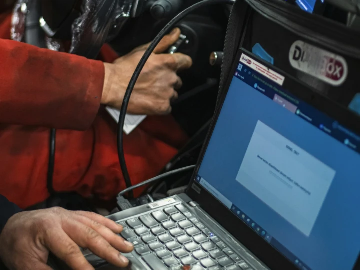 Technician running a diagnostic scan from a laptop plugged into a vehicle