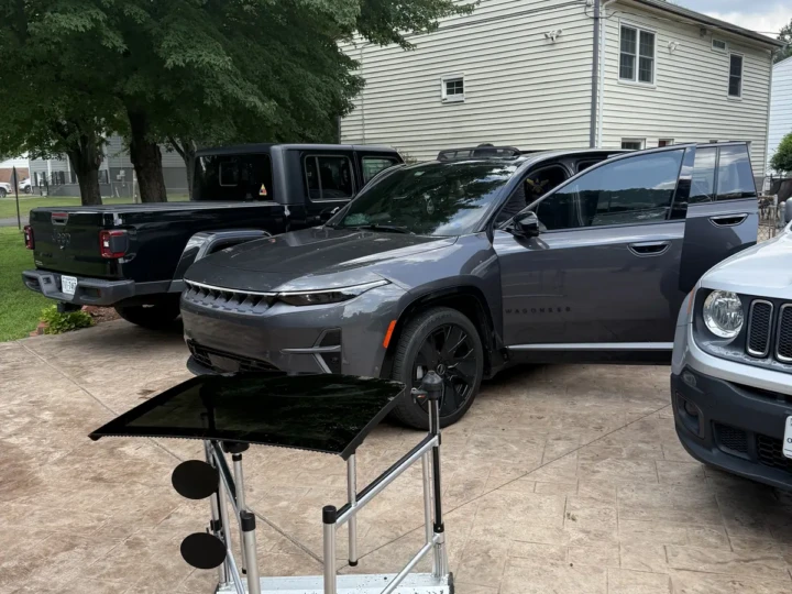 New back glass on a stand beside a Jeep Wagoneer