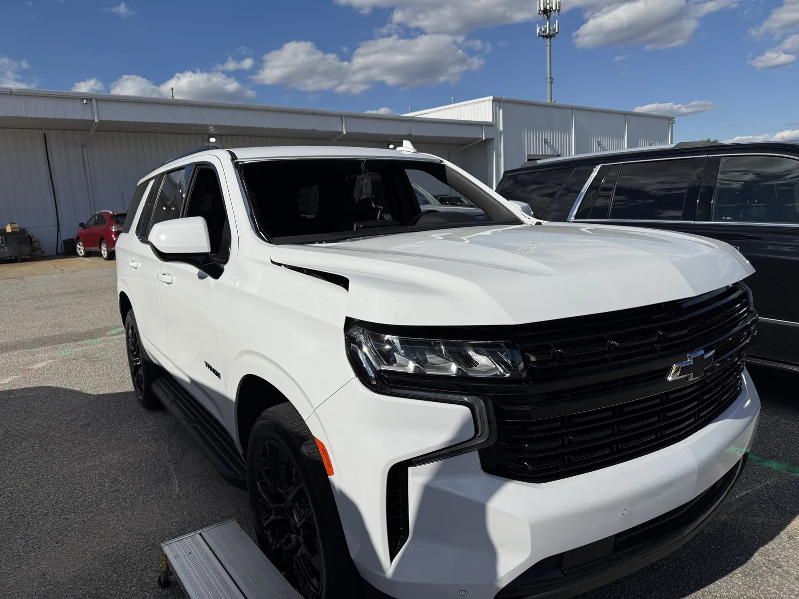 White Chevrolet Tahoe waiting for glass work at the shop