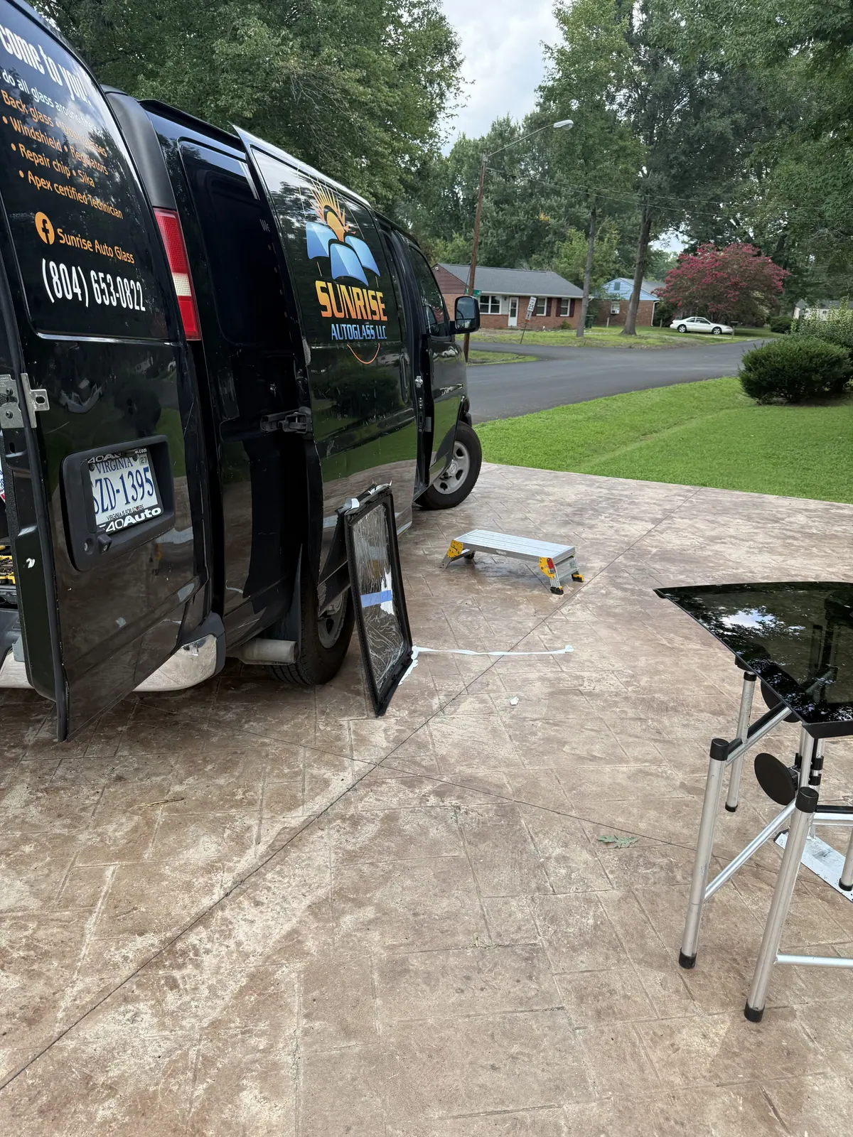 Sunrise AutoGlass van set up in a customer driveway with back glass on a stand
