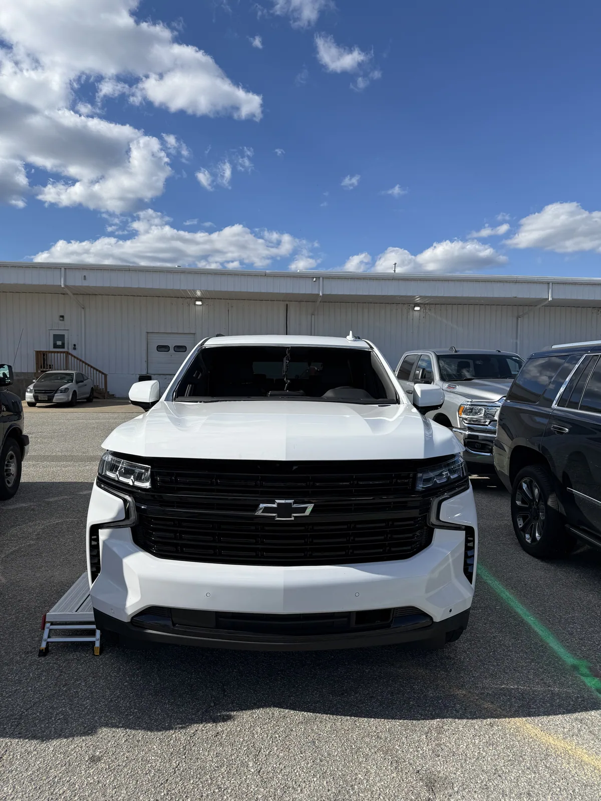 Front of a white Chevrolet Tahoe with camera and sensor area behind the windshield