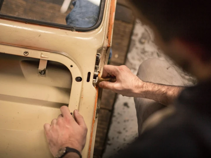 Technician working on the mechanism inside a stripped car door